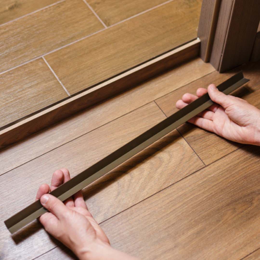 Hands holding a threshold strip in doorway